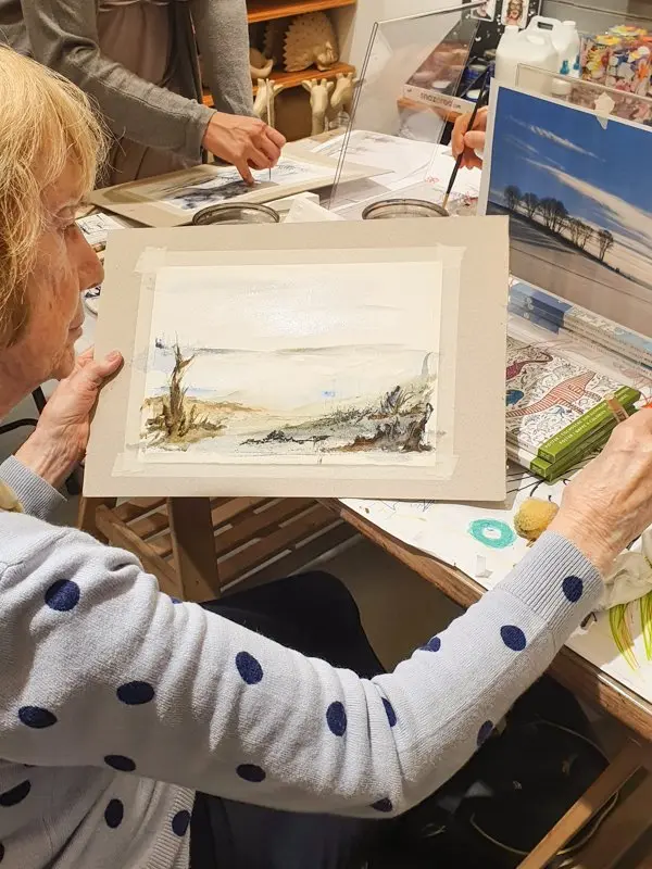 Participants painting together around a table during an Artivian watercolour workshop.